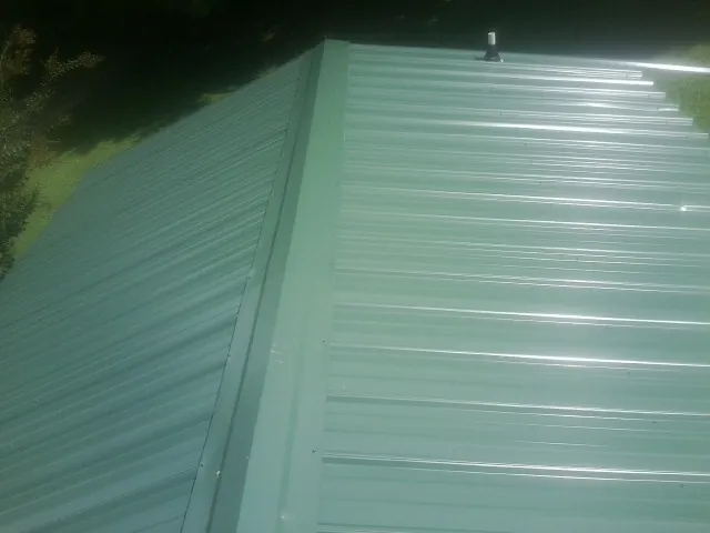 New green metal panels meeting at the ridge of a roof — Flat Roof Repair work by our crew in Robinson