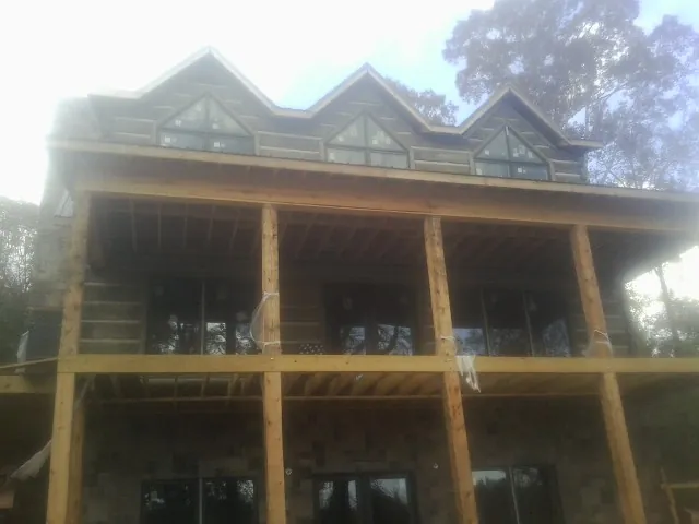 Dormers and porch framing on a large log home under construction — Roof Coating work by our crew in Robinson