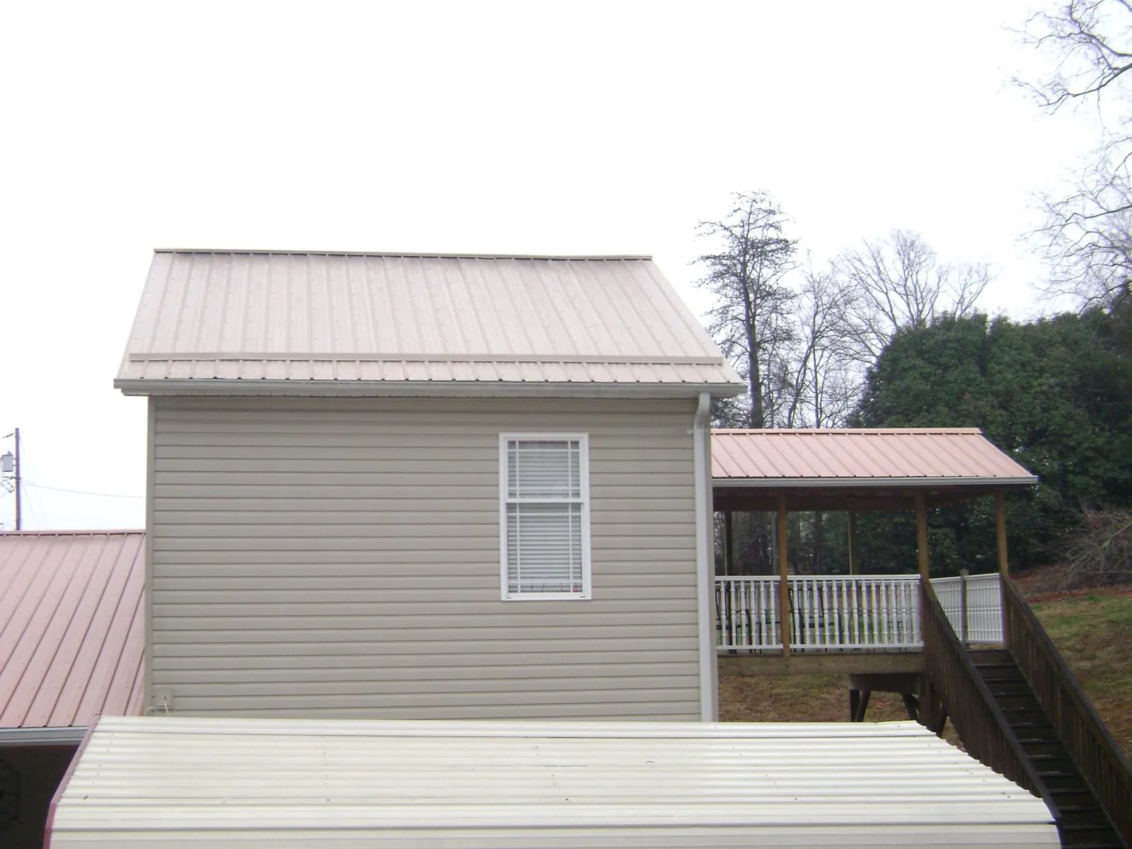 Tan metal roofs on a two story addition and attached porch, from a Roof Replacement job in Robinson