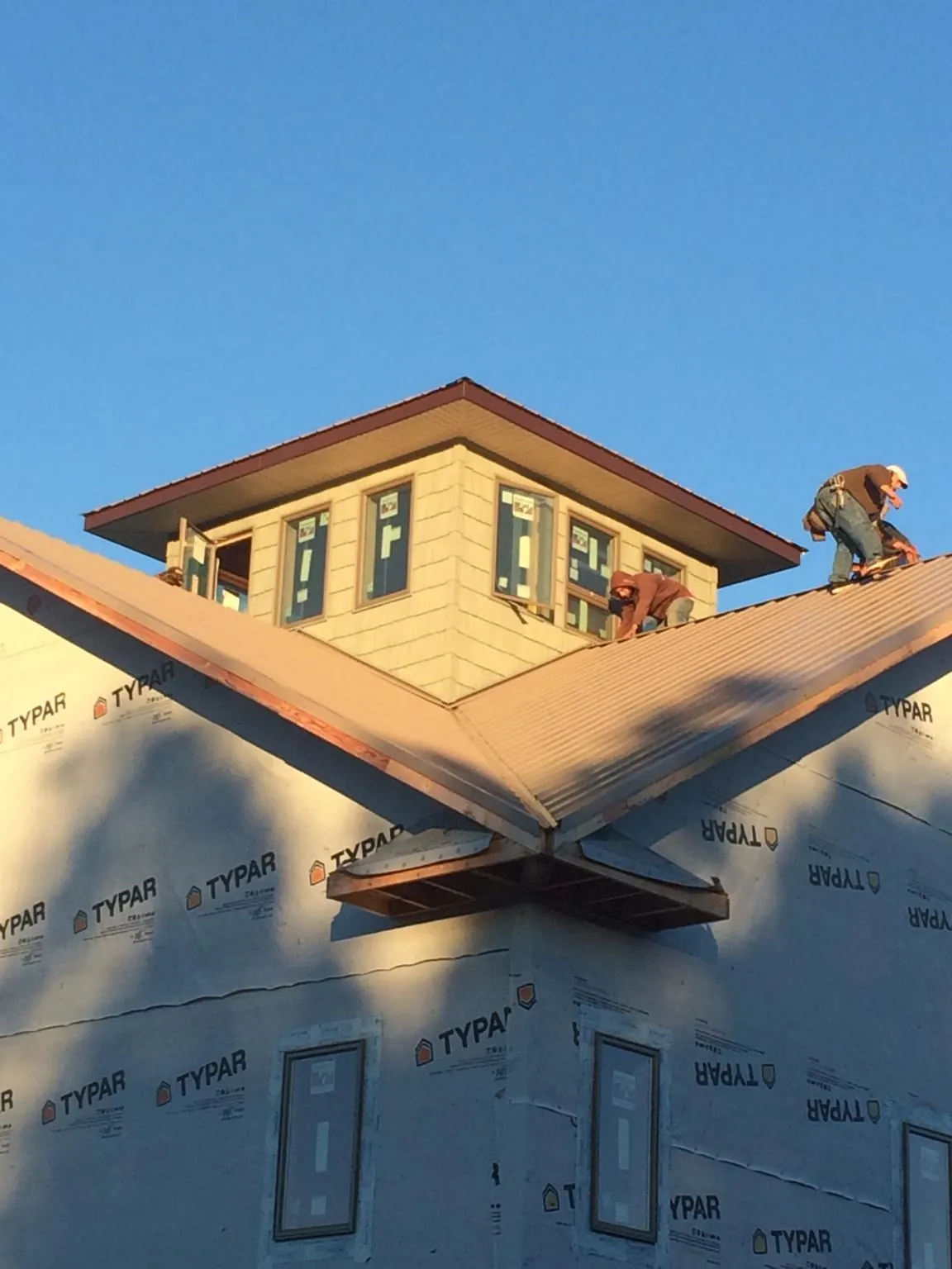 Roofers working around a rooftop cupola on a new metal roof at sunset — Roof Waterproofing in Robinson by Roofing Brothers